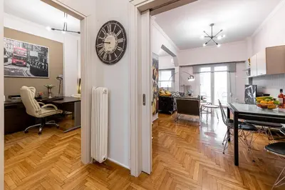 a kitchen and dining room with a clock on the wall at Alopece City Apartment - Kolonaki in Athens