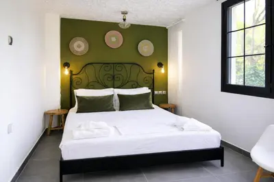 a bedroom with a white bed with a green wall at Villa Xenia&Akis in Athens