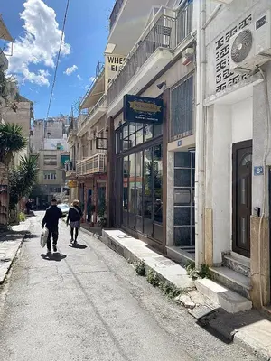two people walking down a street next to a building at Check Point - Museum in Athens