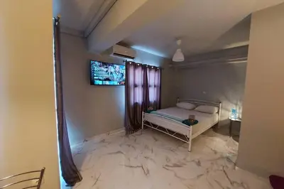 a bedroom with a bed and a tv on the wall at Urban Downtown Studio Back in Athens
