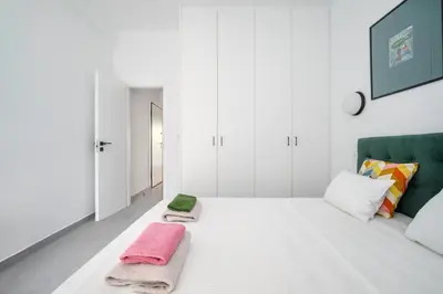 a white bedroom with a bed with two towels on it at Majestic Flat with Huge Terrace in the City Center in Athens
