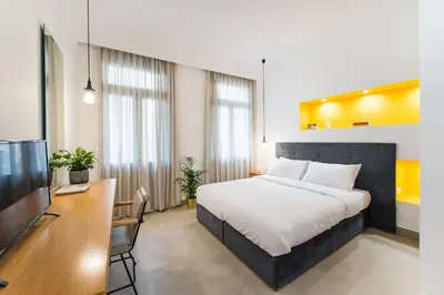 a bedroom with a bed and a desk and a tv at MONK Monastiraki Suites in Athens