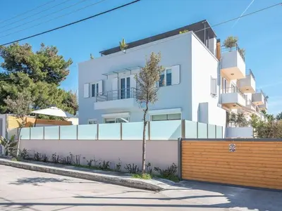 a white house with a fence in front of it at Welcome to Lumen Villa the first of the Adelos Trilogy in Athens