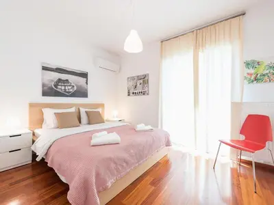 a bedroom with a large bed and a red chair at Adelos Coastal Chic by the Sea - Athens Riviera in Athens