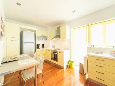 a kitchen with white cabinets and a table with chairs at Adelos Coastal Chic by the Sea - Athens Riviera in Athens