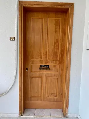 a wooden door in a room with a tile floor at Tiffany's 5' min from airport in Spáta