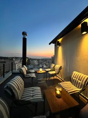 a rooftop patio with couches and tables on a building at Ælis Suites in Psyrri - Rooftop Access & Acropolis View in Athens
