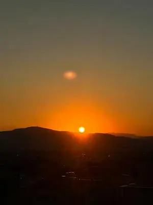 a sunset with the sun setting over a city at Ælis Suites in Psyrri - Rooftop Access & Acropolis View in Athens