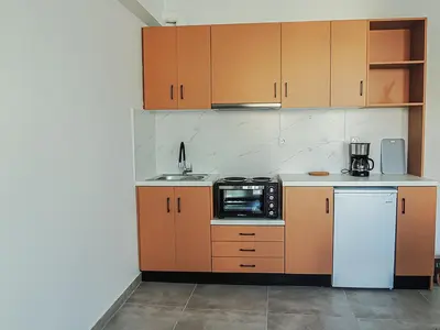 a kitchen with orange cabinets and a sink and a refrigerator at Ælis Suites in Psyrri - Rooftop Access & Acropolis View in Athens