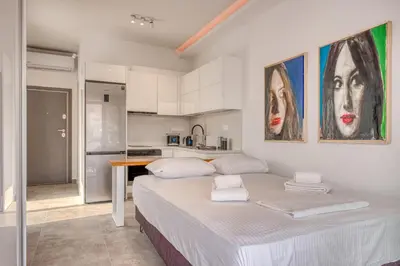 a white bedroom with a large bed and a kitchen at Cozy Deck Roof Apt at the Foothills of Acropolis in Athens