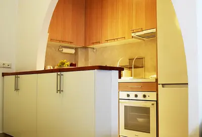 a kitchen with white cabinets and a white oven at Studio Agia Marina Koropi in Aghia Marina