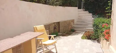 a patio with two chairs and a counter and stairs at Studio Agia Marina Koropi in Aghia Marina