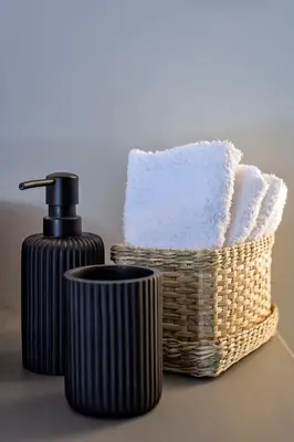 a basket of towels and a soap dispenser next to a towel at Kavouri Seaside Luxury Bungalow in Athens