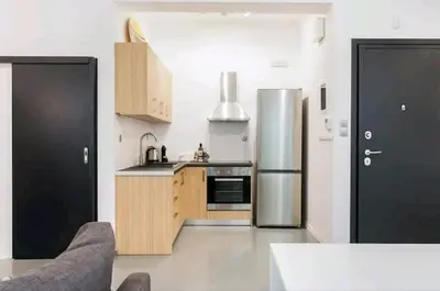 a kitchen with a stainless steel refrigerator and wooden cabinets at Fashionable Base in Central Athens in the Old Tailor Factory in Athens