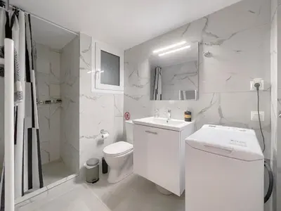 a white bathroom with a toilet and a sink at SOKOS Residence, 4' walk from Syngrou-Fix Metro in Athens