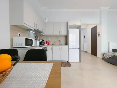 a kitchen and living room with white cabinets and appliances at SOKOS Residence, 4' walk from Syngrou-Fix Metro in Athens