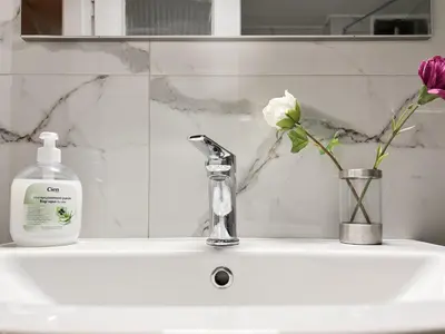a sink with a bottle of soap and a vase with flowers at SOKOS Residence, 5' walk from Acropolis Museum in Athens
