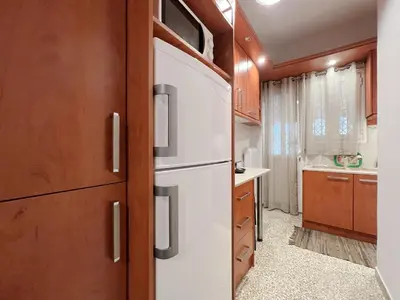 a kitchen with a white refrigerator and wooden cabinets at SOKOS Residence, 5' walk from Acropolis Museum in Athens