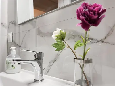 a vase with a purple flower sitting on a bathroom sink at SOKOS Residence, 5' walk from Acropolis Museum in Athens