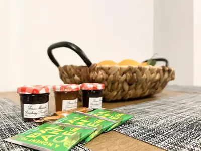 a table with jars of jam and a basket of fruit at SOKOS Residence, 5' walk from Acropolis Museum in Athens