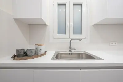 a white kitchen with a sink and cups on a counter at Elegant Suite by CloudKeys in Athens
