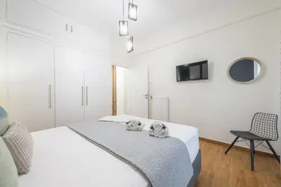 a white bedroom with a bed and a chair at Elegant Suite by CloudKeys in Athens
