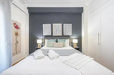 a bedroom with a large white bed with blue walls at Elegant Suite by CloudKeys in Athens