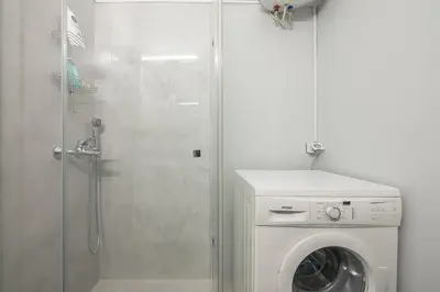 a bathroom with a shower and a washing machine at Stylish Suite by CloudKeys in Athens