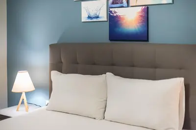 a bed with white pillows and a picture on the wall at Stylish Suite by CloudKeys in Athens