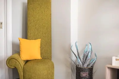 a yellow pillow on a green chair next to a plant at Stylish Suite by CloudKeys in Athens