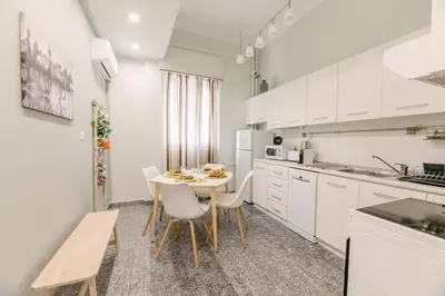 a kitchen with white cabinets and a table and chairs at Ourania by Heloni Apartments in Athens