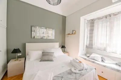 a bedroom with a large white bed and a window at Ourania by Heloni Apartments in Athens