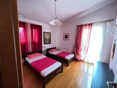 two beds in a room with red curtains at Seaside Villa Lagonisi in Kalívia Thorikoú