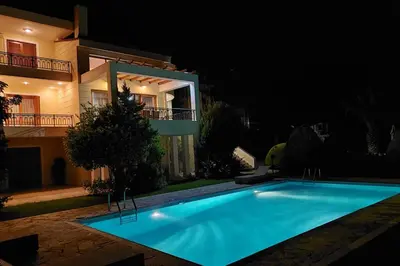 a swimming pool in front of a house at night at Seaside Villa Lagonisi in Kalívia Thorikoú