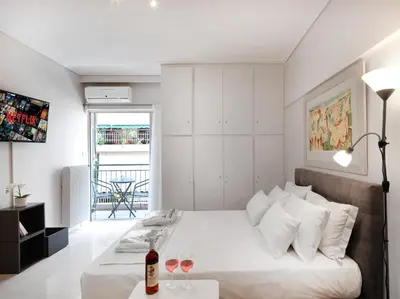 a white bedroom with a bed with two glasses of wine at Modern Studio opposite the Areios Pagos court. in Athens