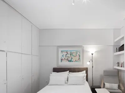 a white bedroom with a bed and a chair at Modern Studio opposite the Areios Pagos court. in Athens
