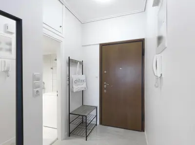 a hallway with a brown door and a chair at Modern Studio opposite the Areios Pagos court. in Athens