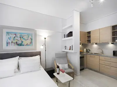 a bedroom with a white bed and a kitchen at Modern Studio opposite the Areios Pagos court. in Athens