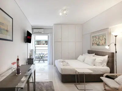 a white bedroom with a large bed and a desk at Modern Studio opposite the Areios Pagos court. in Athens