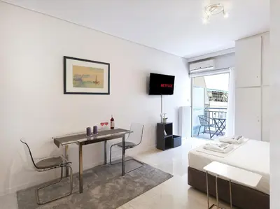 a white living room with a table and a bed at Modern Studio opposite the Areios Pagos court. in Athens
