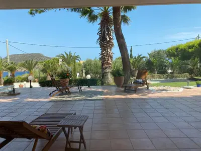 a patio with benches and palm trees and a pool at PortoRafti seaview garden Villa in Porto Rafti