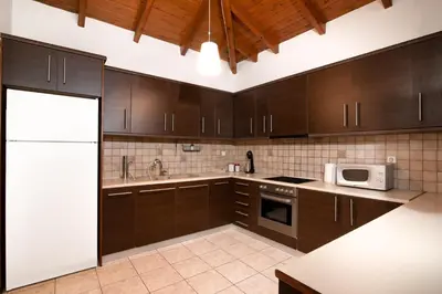 a kitchen with brown cabinets and a white microwave at markopoulo-apartmets in Markopoulo