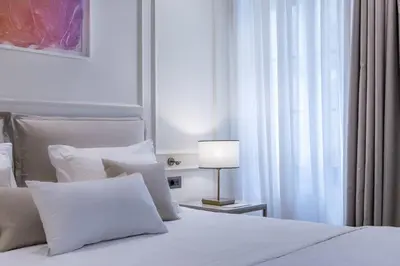 a bedroom with a white bed with a lamp and a window at The Residence Aiolou Hotel & Spa in Athens