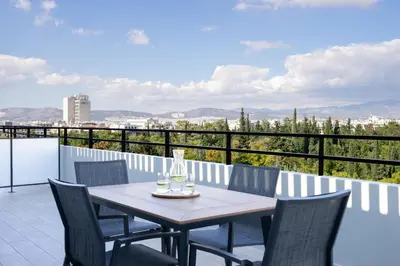 a table and chairs on a balcony with a view at Hestia - Alexandras 38 in Athens