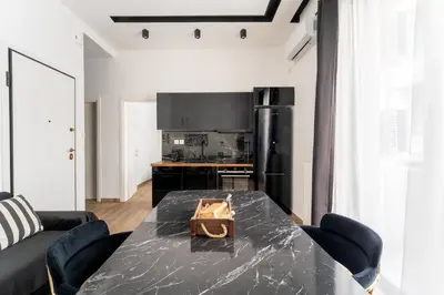 a dining room with a black table and a kitchen at Neo Luxury Suite in Athens