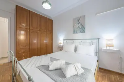 a bedroom with a large white bed with wooden cabinets at Athens Bright Suite by CloudKeys in Athens