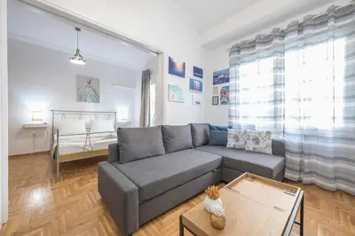 a living room with a gray couch and a table at Athens Bright Suite by CloudKeys in Athens
