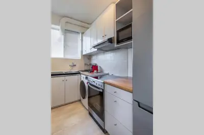 a kitchen with white cabinets and a sink and a dishwasher at Four Seasons Sea View Apartment in Athens