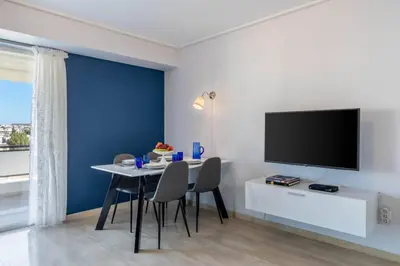 a dining room with a table with chairs and a tv at Four Seasons Sea View Apartment in Athens