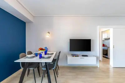 a dining room with a table with chairs and a tv at Four Seasons Sea View Apartment in Athens
